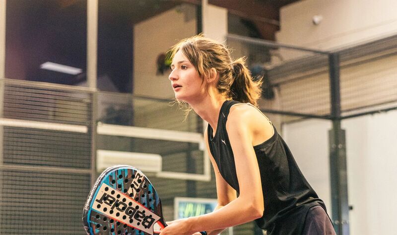 Players learning padel technique on indoor court